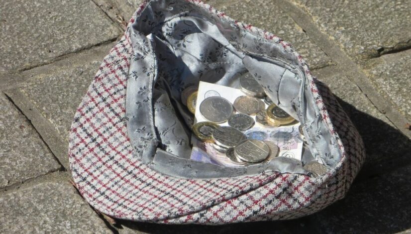 A hat on the floor with coins inside it