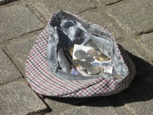 A hat on the floor with coins inside it