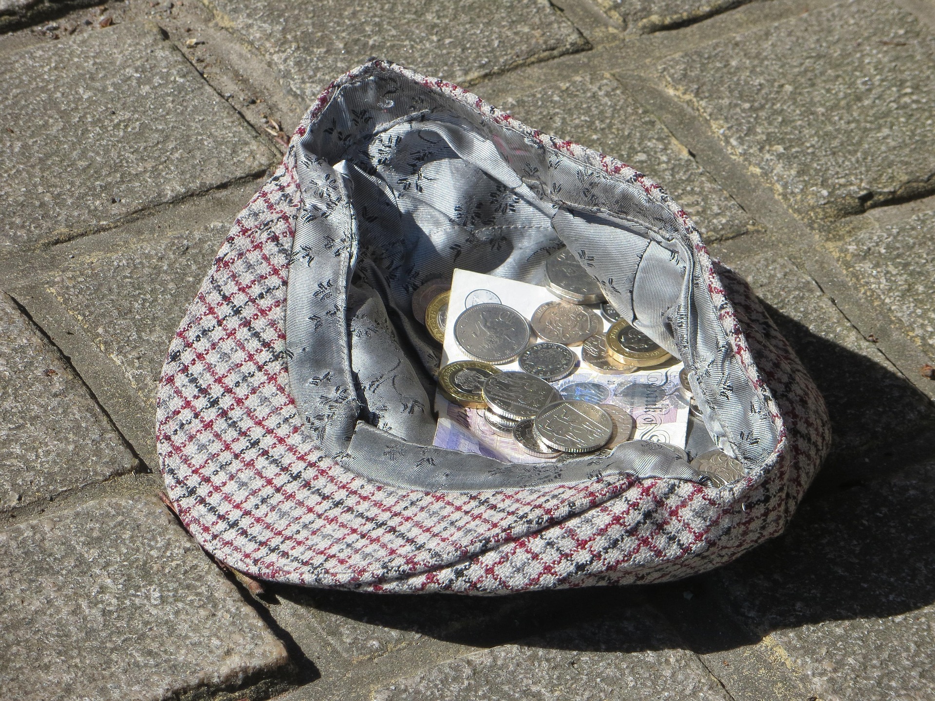 A hat on the floor with coins inside it